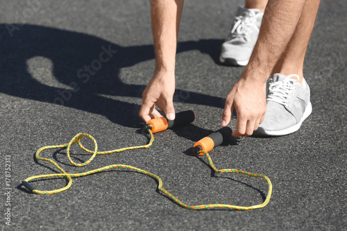 Young man with jumping rope at stadium