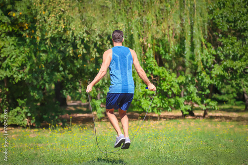 Young man skipping rope in park