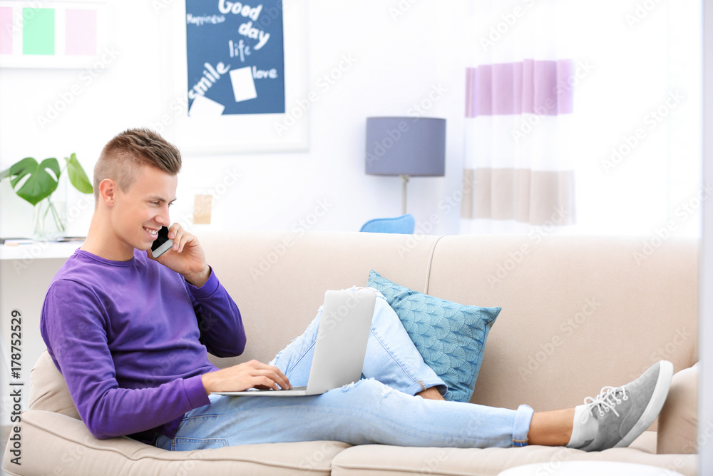 Young man with laptop and cell phone on sofa at home Young man with laptop and cell phone on sofa at home