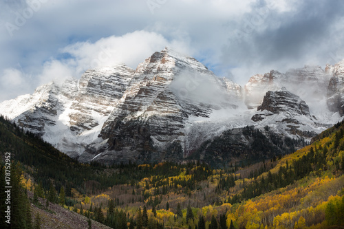 Maroon Bells and yellow gold leaves of aspen trees in a fall foliage autumn season, cloudy sky, Aspen, Colorado, USA.