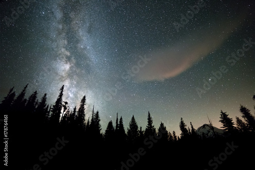 Galaxy rises over dark forest and Mount Hood