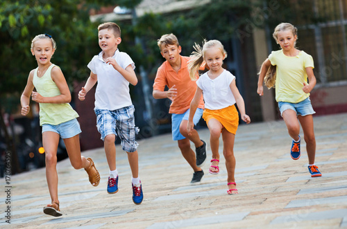 Fototapeta Naklejka Na Ścianę i Meble -  Group of  children running outdoors in city street