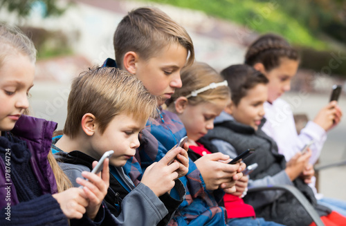 Outdoor portrait of girls and boys playing with phones