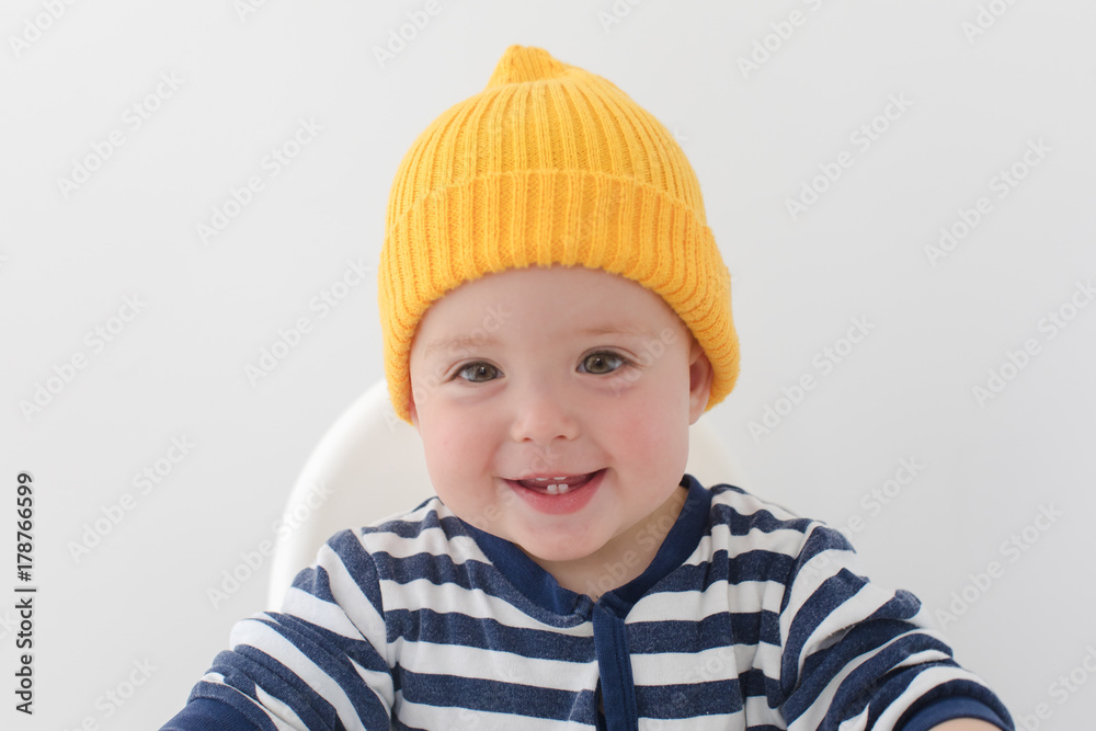 Kid in a yellow hat with two first teeth. Baby with two milk teeth smiling at the camera , studio Kid in a yellow hat with two first teeth. Baby with two milk teeth smiling at the camera , studio