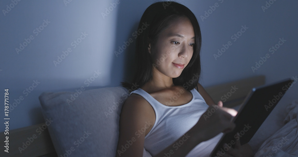Woman using tablet computer at home in the evening Woman using tablet computer at home in the evening