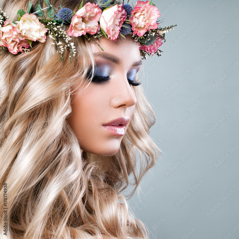 Beautiful Woman with Summer Pink Flowers. Blonde Beauty. Long Permed Curly Hair and Fashion Makeup