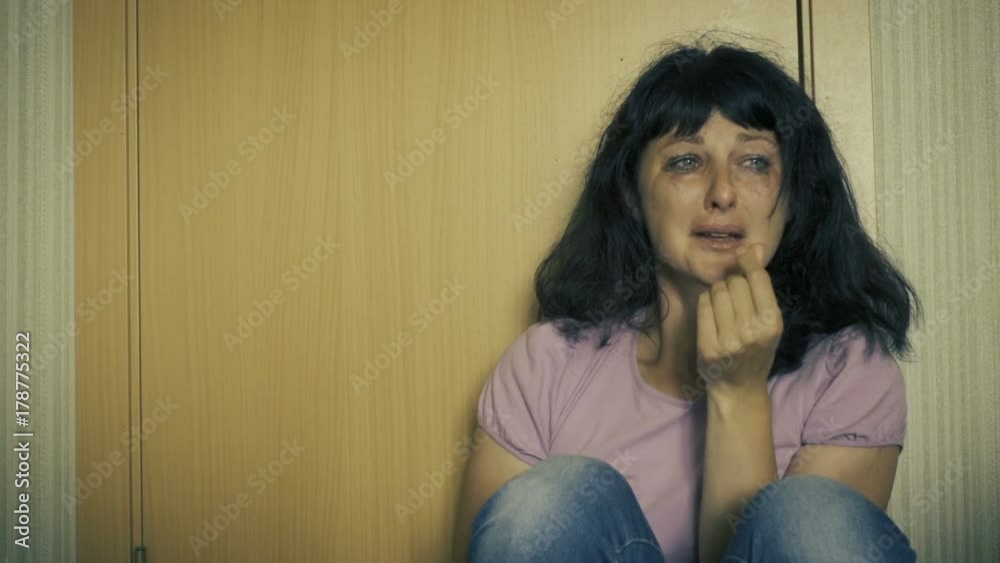 Violence in family. Young raped woman is crying while sitting on floor in corner of room. Close Up Of A Scared And Crying Woman With Smeared Make Up. Girl crying in corner and feeling lonely. Violence in family. Young raped woman is crying while sitting on floor in corner of room. Close Up Of A Scared And Crying Woman With Smeared Make Up. Girl crying in corner and feeling lonely.