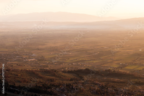 A valley in Umbria at sunset, with mist, close and distant hills and beautiful warm, orange tones © Massimo