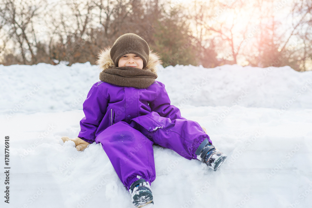 A boy is sitting on a snowbank