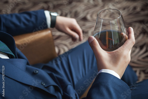 Groom holding glass of whiskey sitting on the chair