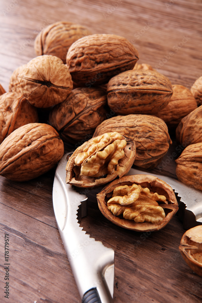 Walnut kernels and whole walnuts on brown wooden table.