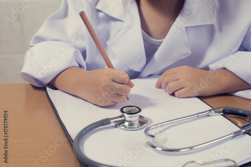 Asian girl wearing as a doctor writing prescription and preparing patients report