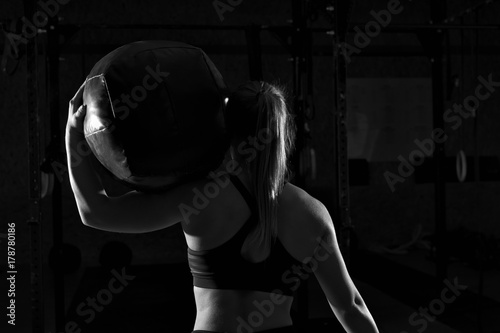 Muscular woman working out in gym with heavy ball