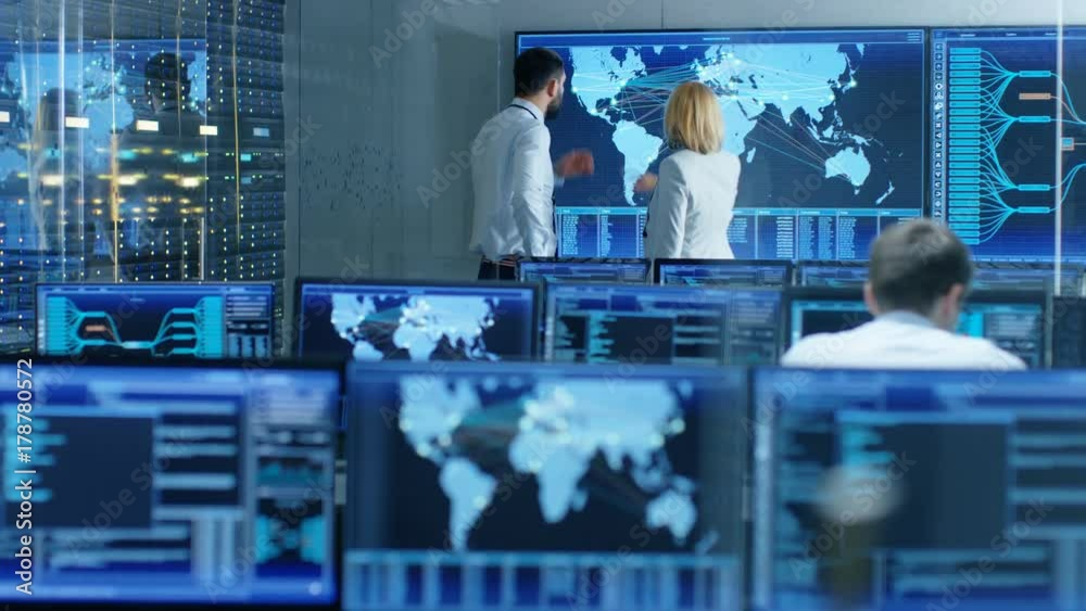 In the System Monitoring Room Two Senior Operators Work on a Big Interactive Map. Facility is Full of Screens Showing Technical Data. Shot on RED EPIC-W 8K Helium Cinema Camera.