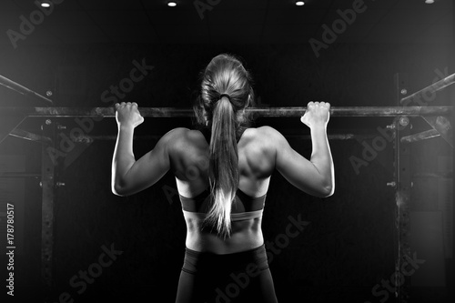 Young fitness female doing pull ups exercise photo