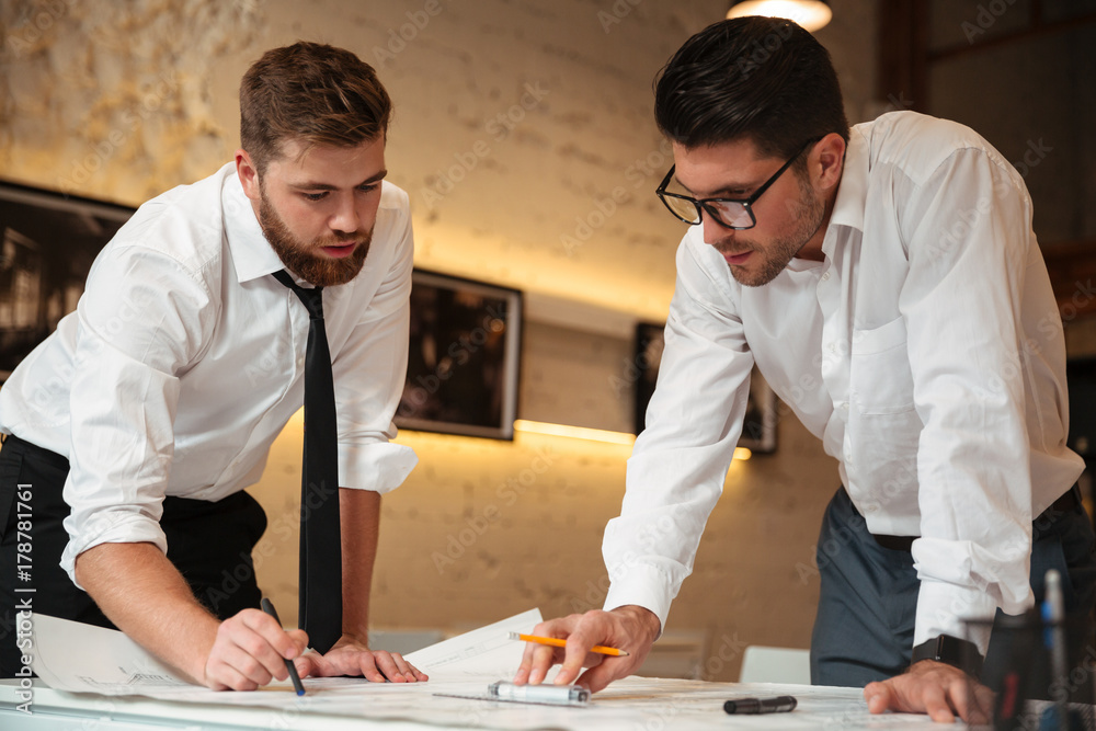 Two young smart businessmen working on a business plan Two young smart businessmen working on a business plan