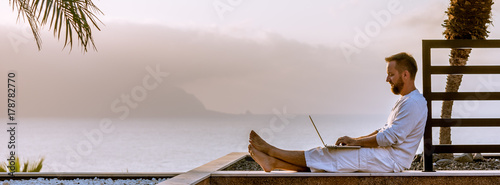 Young man with laptop at sunset