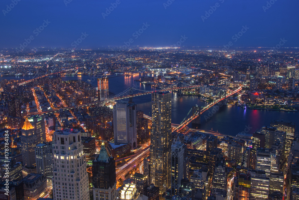 Fototapeta premium New York City Manhattan aerial panorama view at night with office building skyscrapers skyline illuminated by Hudson River.