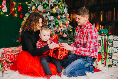 Festive dressed parents sit with their son in the room dressed for Christmas