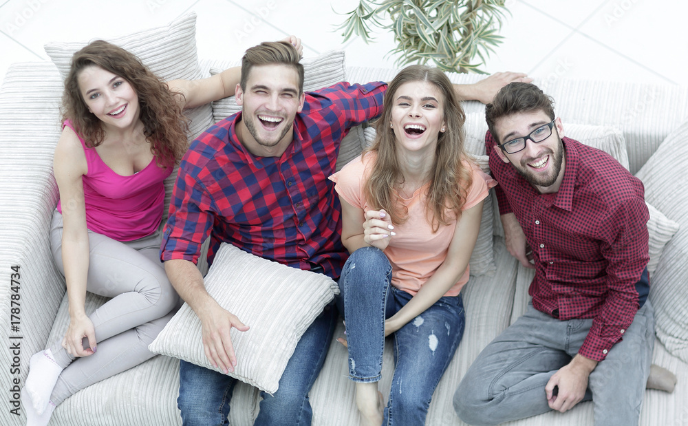 four happy friends laughing while sitting on the couch four happy friends laughing while sitting on the couch