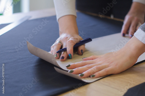 seamstress at work on the table, tailor woman work in studio with clothes 