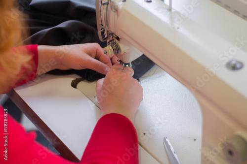 close up picture of seamstress using sewing machine 