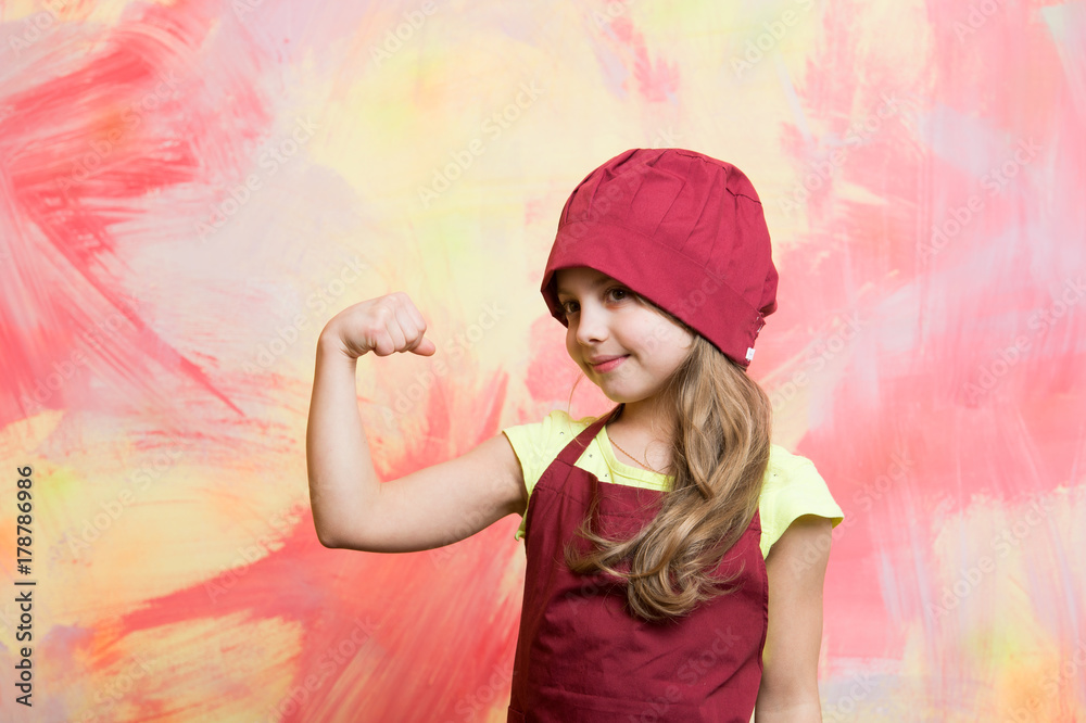 Kid cook flexing hand on colorful wall