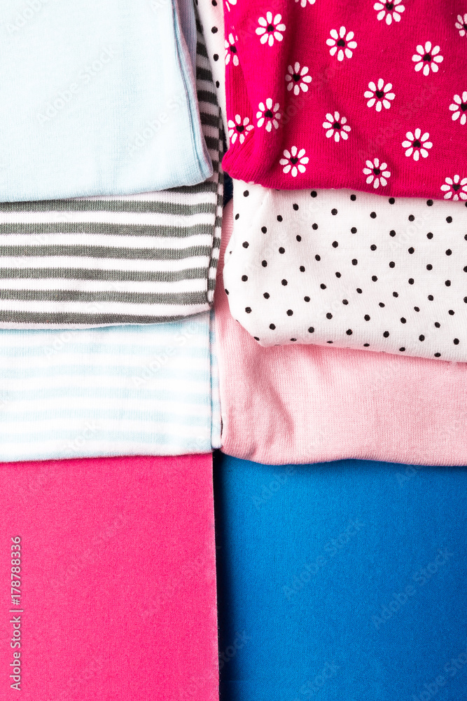 Fototapeta premium Fabric Sewing. Folded blue and pink bodysuit on minimalistic pink and blue background. diaper for newborn boy and girl. Stack of infant clothing. Child outfit. Top view