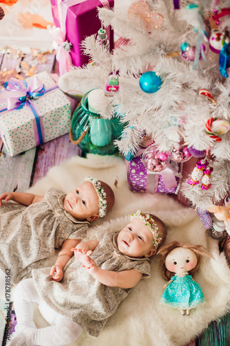 Girl-twins lie under pink Christmas tree