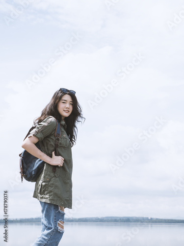 Young asian woman tourist standing with backpack and looking at camera, beautiful backpacker tourism feeling enjoy and happy in her vacation. Traveling, vacation concepts. Copy space. © Ketsada