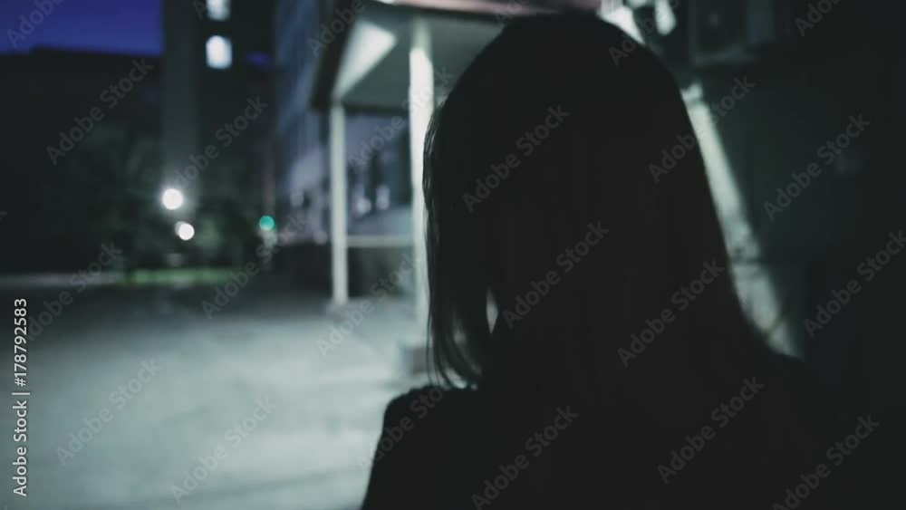 Girl is walking down the street at night
