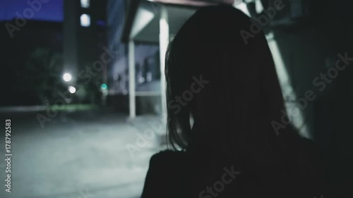 Girl is walking down the street at night