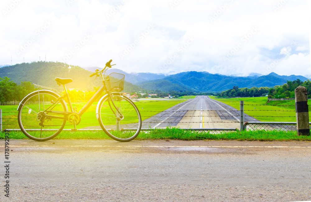 Obraz premium A bicycle stands at near of a runway and mountain with blue sky