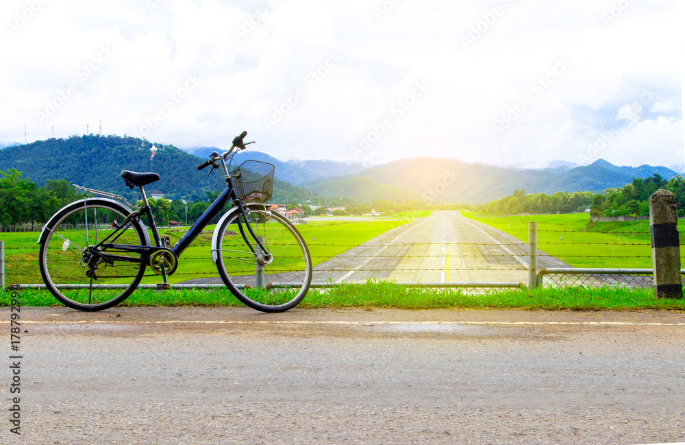 Obraz premium A bicycle stands at near of a runway and mountain with blue sky