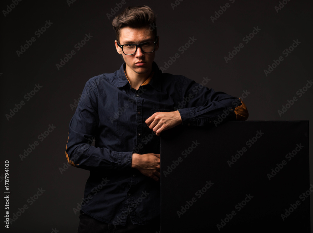 Young confident man portrait of a businessman showing presentation, pointing paper placard black background. Ideal for banners, registration forms, presentation, landings, presenting concept. Young confident man portrait of a businessman showing presentation, pointing paper placard black background. Ideal for banners, registration forms, presentation, landings, presenting concept.