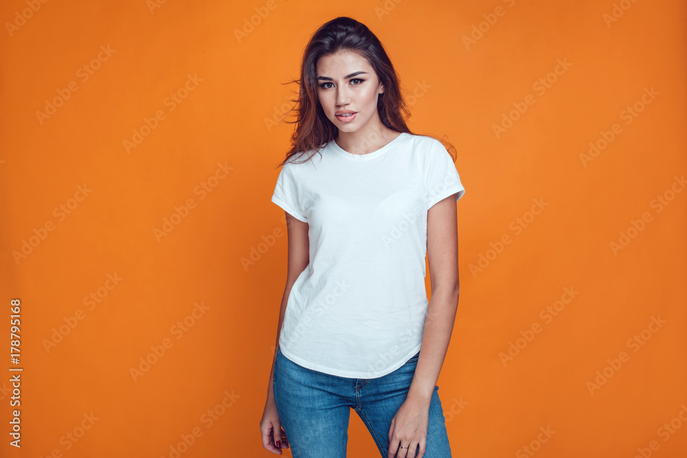 Sexy woman in a white T-shirt on the orange background. Mock-up. - obrazy, fototapety, plakaty 
