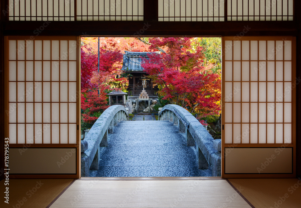 Naklejka premium Bridge and autumn trees seen through the open doors of an old Japanese dojo