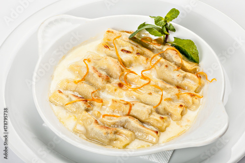 Close-up of the bowl of ravioli bowl of ravioli in white sauce with grated orange peel.
