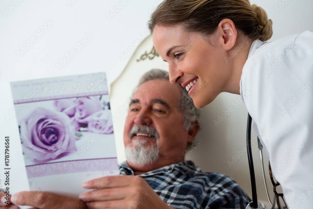 Obraz premium Doctor showing get well card to patient relaxing on bed