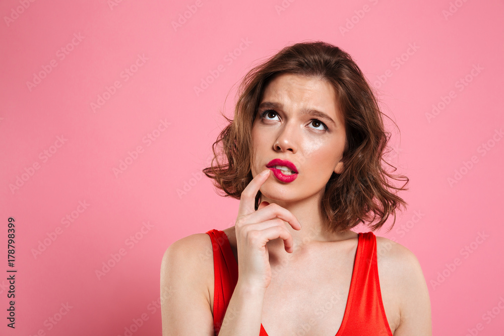 Close-up portrait of thinking young beautiful woman with red lips, touching with finger her cheek, looking upward Close-up portrait of thinking young beautiful woman with red lips, touching with finger her cheek, looking upward