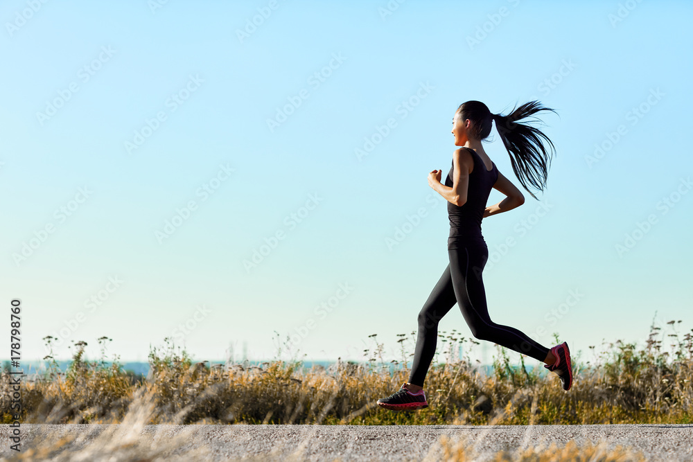 Young athletic woman jogging on rural road in early morning Young athletic woman jogging on rural road in early morning