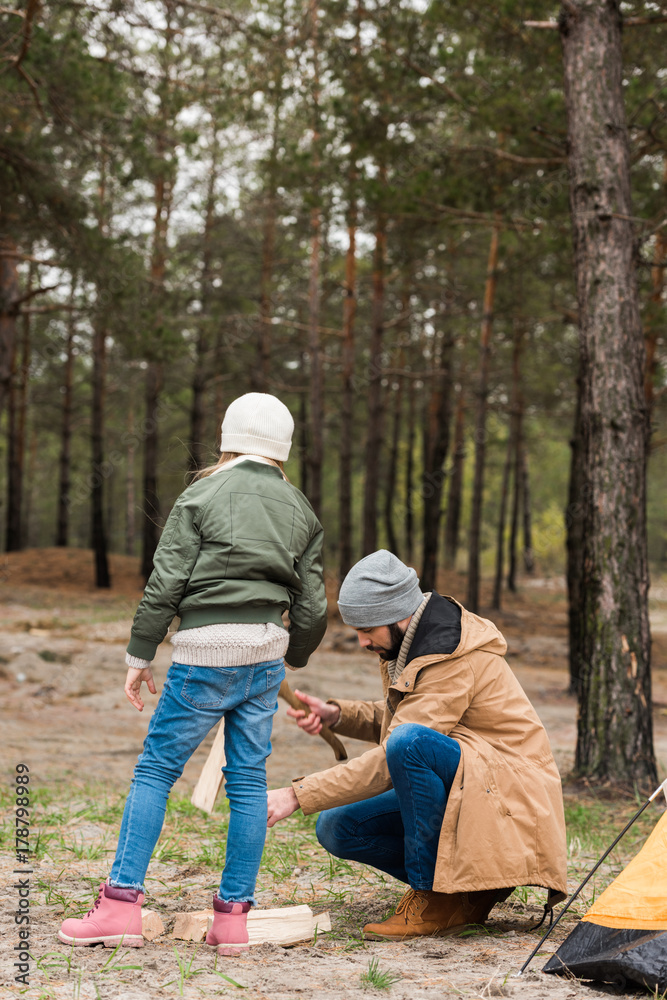father and daughter preparing logs for campfire father and daughter preparing logs for campfire
