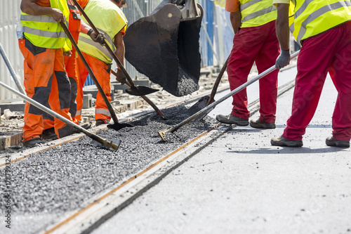 Workers construct asphalt road and railroad lines