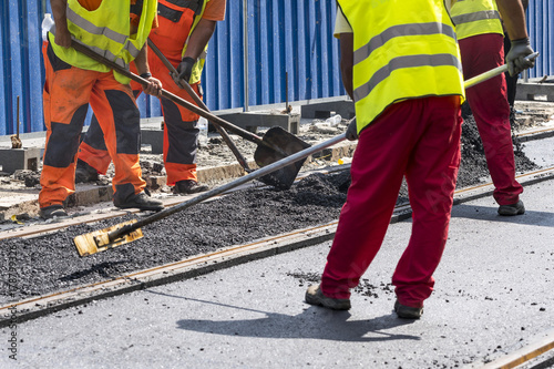 Workers construct asphalt road and railroad lines