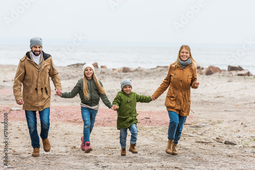 family holding hands and walking by seashore