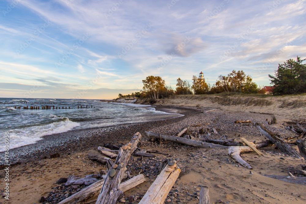 Scenic Autumn Lake Superior Beach Background. Driftwood beach on Lake Superior with the Whitefish Point Lighthouse. Whitefish Point is in the Upper Peninsula of Michigan on the shipwreck coast.