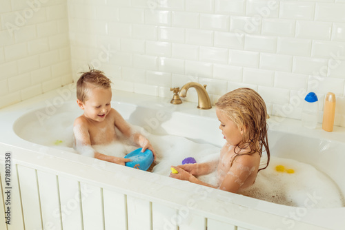 Photography kids playing in bathtub with foam