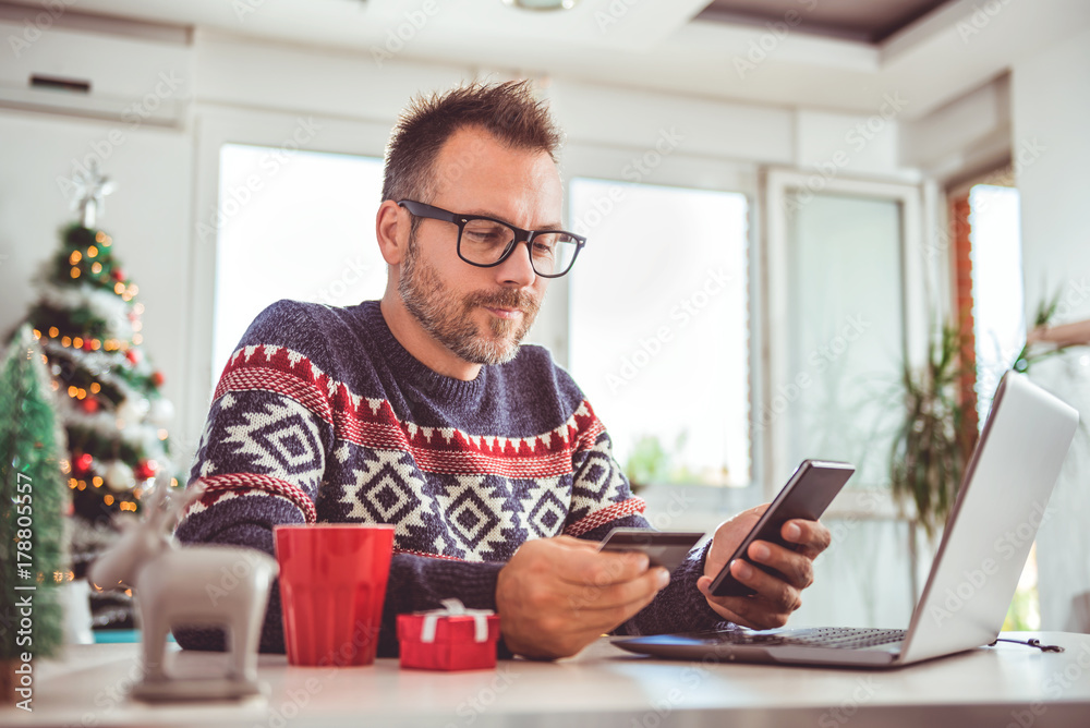 Men holding credit card and using laptop at home office Men holding credit card and using laptop at home office