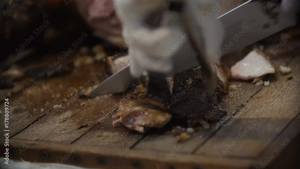 The cook cuts the cooked meat of the carcass of the pig. Delicious juicy roasted pork The cook cuts the cooked meat of the carcass of the pig. Delicious juicy roasted pork