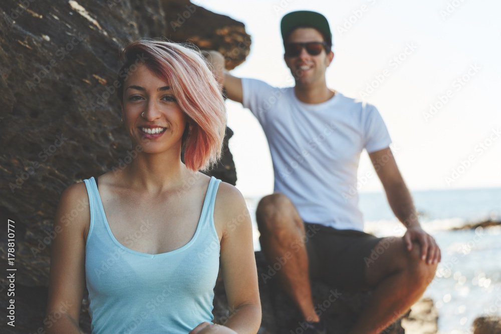 Obraz premium Young woman sitting on rock with friend smiling